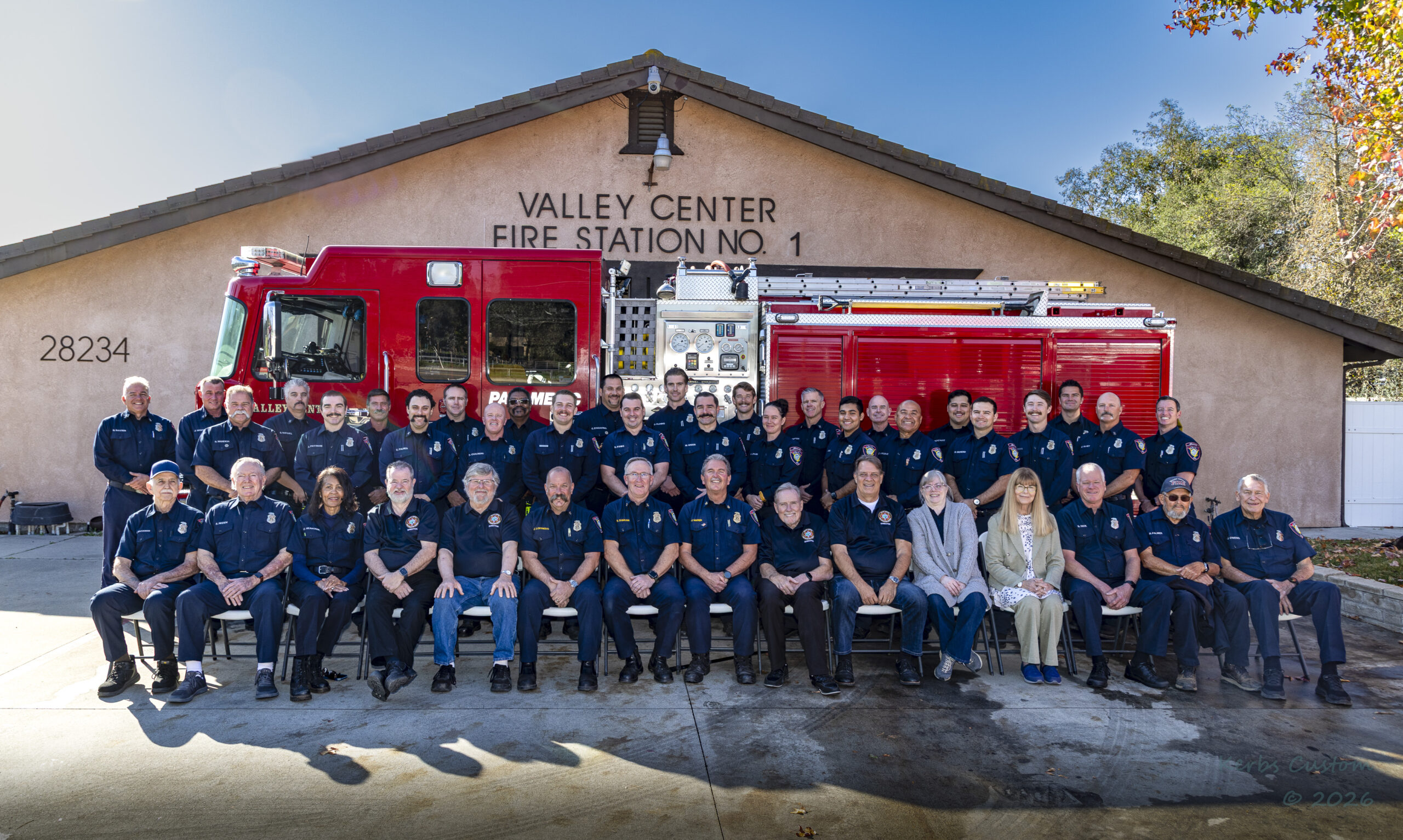Valley Center firefighters and community members gathered in front of Fire Station No. 1 and a red fire engine.