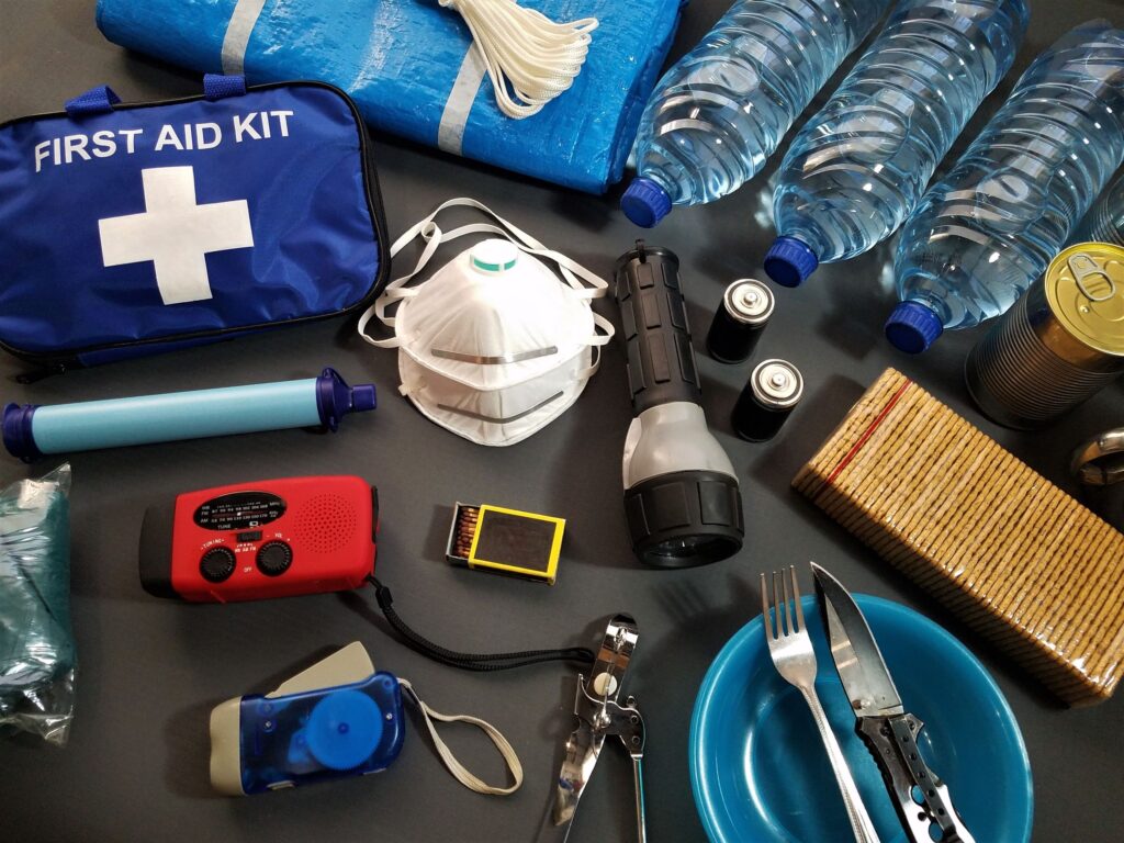 Flat lay of essential emergency survival kit items including first aid and water bottles.